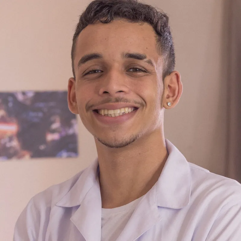 Omar Haddad, a young man in a white clinical coat, smiling