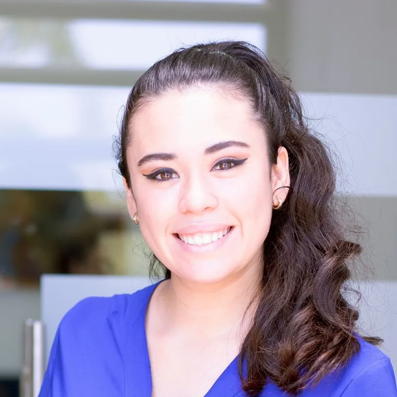 Rosa Fenwick, a young woman in blue scrubs, smiling