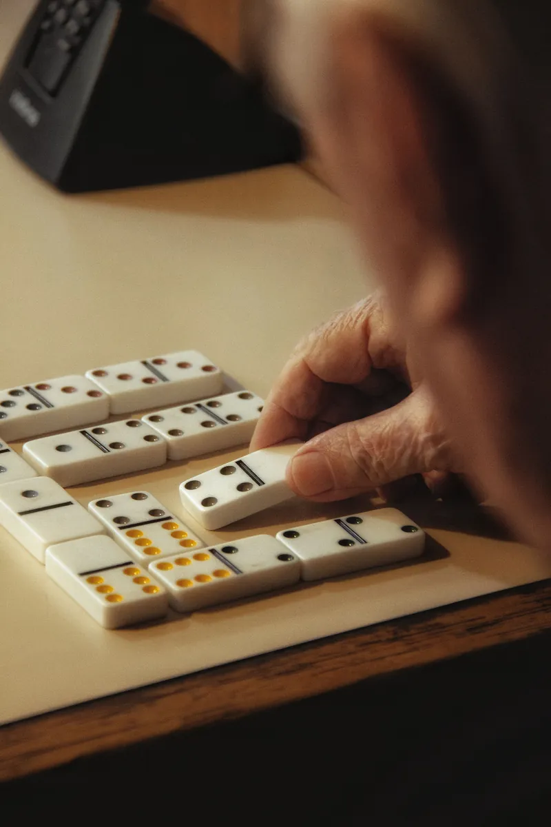 A resident's hand placing a domino on the table.
