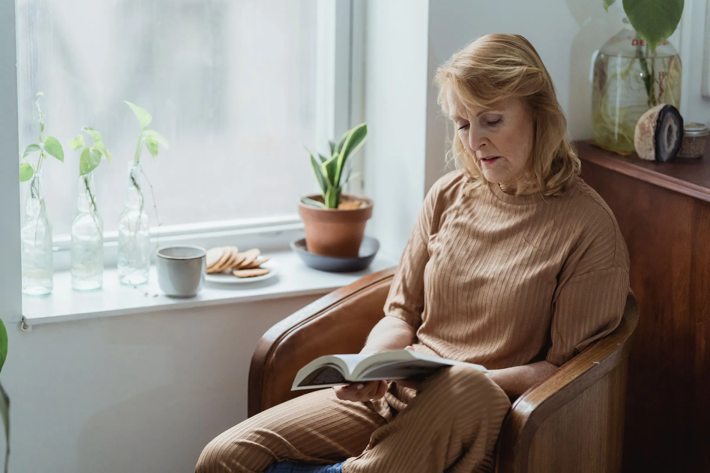A resident reading in an armchair by the window, tea on the sill.